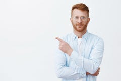 Κοιτάξτε εκεί τώρα Πορτρέτο του όμορφου redhead αρσενικού με τη γενειάδα σε eyewear και του πουκάμισου που δείχνει στην ανώτερη α στοκ εικόνες με δικαίωμα ελεύθερης χρήσης Κοιτάξτε εκεί τώρα Πορτρέτο του όμορφου redhead αρσενικού με τη γενειάδα σε eyewear και του πουκάμισου που δείχνει στην ανώτερη α στοκ εικόνες με δικαίωμα ελεύθερης χρήσης