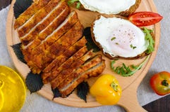 Κομμάτια της μπριζόλας schnitzel, φρυγανιά με τα αυγά, φρέσκια ντομάτα σε έναν ξύλινο πίνακα σε ένα σκοτεινό υπόβαθρο Στοκ φωτογραφίες με δικαίωμα ελεύθερης χρήσης Κομμάτια της μπριζόλας schnitzel, φρυγανιά με τα αυγά, φρέσκια ντομάτα σε έναν ξύλινο πίνακα σε ένα σκοτεινό υπόβαθρο Στοκ φωτογραφίες με δικαίωμα ελεύθερης χρήσης