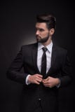 Κομψό κούμπωμα κοστουμιών νεαρών άνδρων, που κοιτάζει λοξά Στοκ εικόνα με δικαίωμα ελεύθερης χρήσης Κομψό κούμπωμα κοστουμιών νεαρών άνδρων, που κοιτάζει λοξά Στοκ εικόνα με δικαίωμα ελεύθερης χρήσης