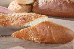 Κοπή Baguette στο υπόβαθρο των κουλουριών και του ψωμιού στοκ φωτογραφίες Κοπή Baguette στο υπόβαθρο των κουλουριών και του ψωμιού στοκ φωτογραφίες