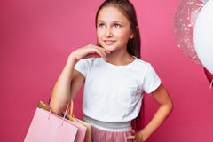 Κορίτσι εφήβων με τις τσάντες αγορών υπό εξέταση, στο ρόδινο υπόβαθρο, με τα μπαλόνια στοκ εικόνα Κορίτσι εφήβων με τις τσάντες αγορών υπό εξέταση, στο ρόδινο υπόβαθρο, με τα μπαλόνια στοκ εικόνα