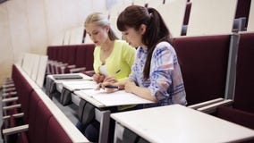 Κορίτσια σπουδαστών με τα σημειωματάρια στην αίθουσα διάλεξης απόθεμα βίντεο Κορίτσια σπουδαστών με τα σημειωματάρια στην αίθουσα διάλεξης απόθεμα βίντεο