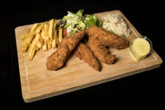 Κοτόπουλο Goujons που εξυπηρετείται με το ρύζι, τη σαλάτα και τις τηγανιτές πατάτες στο ξύλο στοκ φωτογραφία με δικαίωμα ελεύθερης χρήσης Κοτόπουλο Goujons που εξυπηρετείται με το ρύζι, τη σαλάτα και τις τηγανιτές πατάτες στο ξύλο στοκ φωτογραφία με δικαίωμα ελεύθερης χρήσης