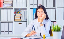 Κουρασμένος θηλυκός ιατρός στην άσπρη ιατρική εσθήτα επιδέσμου που περιμένει τους ασθενείς στο γραφείο Στοκ φωτογραφίες με δικαίωμα ελεύθερης χρήσης Κουρασμένος θηλυκός ιατρός στην άσπρη ιατρική εσθήτα επιδέσμου που περιμένει τους ασθενείς στο γραφείο Στοκ φωτογραφίες με δικαίωμα ελεύθερης χρήσης