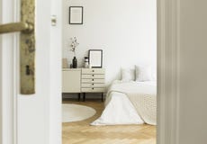 Κρυφοκοιτάξτε μέσω μιας πόρτας σε ένα μονοχρωματικό, λευκό εσωτερικό κρεβατοκάμαρων με ένα κρεβάτι και τα γραφεία που στέκονται σ στοκ εικόνες Κρυφοκοιτάξτε μέσω μιας πόρτας σε ένα μονοχρωματικό, λευκό εσωτερικό κρεβατοκάμαρων με ένα κρεβάτι και τα γραφεία που στέκονται σ στοκ εικόνες