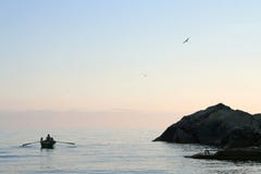 Κωπηλασία ανθρώπων στη θάλασσα στο ηλιοβασίλεμα Γλάροι στον ουρανό στοκ φωτογραφία Κωπηλασία ανθρώπων στη θάλασσα στο ηλιοβασίλεμα Γλάροι στον ουρανό στοκ φωτογραφία