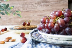 Κόκκινα σταφύλια δεσμών στο μπλε κύπελλο, στο ξύλινο κλίμα στοκ φωτογραφία με δικαίωμα ελεύθερης χρήσης Κόκκινα σταφύλια δεσμών στο μπλε κύπελλο, στο ξύλινο κλίμα στοκ φωτογραφία με δικαίωμα ελεύθερης χρήσης