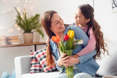 Κόρη ημέρας της μητέρας μητέρων και κορών στο σπίτι που αγκαλιάζει τη μητέρα με την ανθοδέσμη των λουλουδιών ευτυχών στοκ φωτογραφία με δικαίωμα ελεύθερης χρήσης Κόρη ημέρας της μητέρας μητέρων και κορών στο σπίτι που αγκαλιάζει τη μητέρα με την ανθοδέσμη των λουλουδιών ευτυχών στοκ φωτογραφία με δικαίωμα ελεύθερης χρήσης