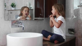 Λίγο χαριτωμένο κορίτσι βουρτσίζει τα δόντια της με το οδοντικό νήμα μπροστά από τον καθρέφτη φιλμ μικρού μήκους Λίγο χαριτωμένο κορίτσι βουρτσίζει τα δόντια της με το οδοντικό νήμα μπροστά από τον καθρέφτη φιλμ μικρού μήκους