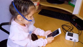 Λίγο χαριτωμένο κορίτσι θεραπεύεται με nebulizer και χρησιμοποιεί ένα κινητό τηλέφωνο απόθεμα βίντεο Λίγο χαριτωμένο κορίτσι θεραπεύεται με nebulizer και χρησιμοποιεί ένα κινητό τηλέφωνο απόθεμα βίντεο