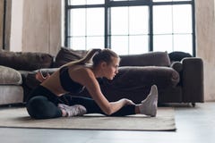 Λεπτή φίλαθλος sportswear στους μυς προθέρμανσης πριν από το workout που κάνει την τεντώνοντας συνεδρίαση άσκησης στο πάτωμα στο στοκ εικόνες με δικαίωμα ελεύθερης χρήσης Λεπτή φίλαθλος sportswear στους μυς προθέρμανσης πριν από το workout που κάνει την τεντώνοντας συνεδρίαση άσκησης στο πάτωμα στο στοκ εικόνες με δικαίωμα ελεύθερης χρήσης