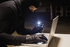 Ληστής που χαράσσει ένα lap-top κάνοντας το φως με το τηλέφωνό του Στοκ Εικόνες Ληστής που χαράσσει ένα lap-top κάνοντας το φως με το τηλέφωνό του Στοκ Εικόνες