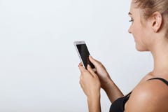 Λοξά πορτρέτο του θηλυκού με το υγιές καθαρό δέρμα που κρατά το κινητό τηλέφωνο στα χέρια με την κενή οθόνη, που διαβάζει τις ειδ στοκ εικόνες Λοξά πορτρέτο του θηλυκού με το υγιές καθαρό δέρμα που κρατά το κινητό τηλέφωνο στα χέρια με την κενή οθόνη, που διαβάζει τις ειδ στοκ εικόνες