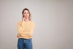 Μέση-επάνω στο πορτρέτο της ξανθής γυναίκας με την μπερδεμένη έκφραση προσώπου, κρατά το δάχτυλό της στο μάγουλο, κοιτάζει κατά μ στοκ εικόνες Μέση-επάνω στο πορτρέτο της ξανθής γυναίκας με την μπερδεμένη έκφραση προσώπου, κρατά το δάχτυλό της στο μάγουλο, κοιτάζει κατά μ στοκ εικόνες