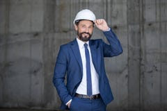 Μέσος ηλικίας επιχειρηματίας στο σκληρό καπέλο και κοστούμι που στέκεται και που χαμογελά στην εργασία Στοκ Φωτογραφία Μέσος ηλικίας επιχειρηματίας στο σκληρό καπέλο και κοστούμι που στέκεται και που χαμογελά στην εργασία Στοκ Φωτογραφία