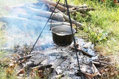 Μαγειρεύοντας τρόφιμα στην κατσαρόλα στην πυρκαγιά καυσόξυλου στο πικ-νίκ το καλοκαίρι στοκ εικόνες Μαγειρεύοντας τρόφιμα στην κατσαρόλα στην πυρκαγιά καυσόξυλου στο πικ-νίκ το καλοκαίρι στοκ εικόνες