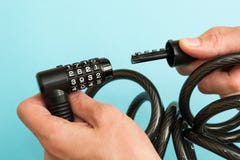Μαύρη κλειδαριά ποδηλάτων με τον κώδικα στα χέρια σε ένα μπλε υπόβαθρο στοκ φωτογραφίες Μαύρη κλειδαριά ποδηλάτων με τον κώδικα στα χέρια σε ένα μπλε υπόβαθρο στοκ φωτογραφίες
