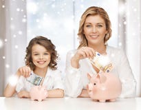 Μητέρα και κόρη με τις piggy τράπεζες και τα χρήματα στοκ εικόνες με δικαίωμα ελεύθερης χρήσης Μητέρα και κόρη με τις piggy τράπεζες και τα χρήματα στοκ εικόνες με δικαίωμα ελεύθερης χρήσης