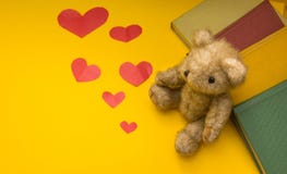 Μια teddy αρκούδα κάθεται κοντά στα βιβλία σε ένα κίτρινο υπόβαθρο των δι στοκ εικόνες Μια teddy αρκούδα κάθεται κοντά στα βιβλία σε ένα κίτρινο υπόβαθρο των δι στοκ εικόνες