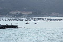 Μια βάρκα μηχανών και μια βάρκα κωπηλασίας μπαίνουν στο λιμένα του Λα Spezia στοκ εικόνα Μια βάρκα μηχανών και μια βάρκα κωπηλασίας μπαίνουν στο λιμένα του Λα Spezia στοκ εικόνα