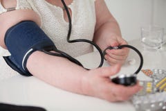 Μια γυναίκα μετρά την πίεσή της με ένα sphygmomanometer μόνο στοκ εικόνες Μια γυναίκα μετρά την πίεσή της με ένα sphygmomanometer μόνο στοκ εικόνες