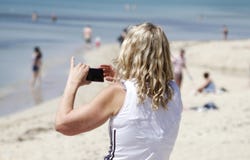 Μια γυναίκα παίρνει μια εικόνα με το κύτταρό της Arenal στην παραλία στοκ εικόνες Μια γυναίκα παίρνει μια εικόνα με το κύτταρό της Arenal στην παραλία στοκ εικόνες