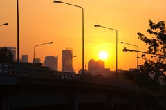Μια ζωηρόχρωμη ανατολή των πορτοκαλιών και κίτρινων χρωμάτων, πέρα από τη σκοτεινή σκιαγραφία μιας γέφυρας στη Μπανγκόκ, Ταϊλάνδη στοκ φωτογραφία με δικαίωμα ελεύθερης χρήσης Μια ζωηρόχρωμη ανατολή των πορτοκαλιών και κίτρινων χρωμάτων, πέρα από τη σκοτεινή σκιαγραφία μιας γέφυρας στη Μπανγκόκ, Ταϊλάνδη στοκ φωτογραφία με δικαίωμα ελεύθερης χρήσης