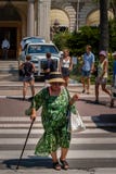 Μια ηλικιωμένη κυρία διασχίζει τη λεωφόρο μπροστά από το ξενοδοχείο του Carlton, Κάννες στοκ φωτογραφία Μια ηλικιωμένη κυρία διασχίζει τη λεωφόρο μπροστά από το ξενοδοχείο του Carlton, Κάννες στοκ φωτογραφία