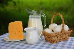 Μια κανάτα γάλακτος, ένα καλάθι των αυγών, ένας κορφολόγος, και ένα κομμάτι του τυριού στοκ φωτογραφία Μια κανάτα γάλακτος, ένα καλάθι των αυγών, ένας κορφολόγος, και ένα κομμάτι του τυριού στοκ φωτογραφία