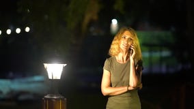 Μια λεπτή λυπημένη γυναίκα με την ξανθή σγουρή τρίχα του Μεσαίωνα που μιλά στο τηλέφωνο κοντά σε ένα φωτεινό βράδυ πρόσφατου καλο απόθεμα βίντεο Μια λεπτή λυπημένη γυναίκα με την ξανθή σγουρή τρίχα του Μεσαίωνα που μιλά στο τηλέφωνο κοντά σε ένα φωτεινό βράδυ πρόσφατου καλο απόθεμα βίντεο