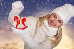Μια νέα γυναίκα στα όμορφα άσπρα πλεκτά ενδύματα κρατά την ξύλινη διακόσμηση Χριστουγέννων αλόγων για το χριστουγεννιάτικο δέντρο στοκ φωτογραφία με δικαίωμα ελεύθερης χρήσης Μια νέα γυναίκα στα όμορφα άσπρα πλεκτά ενδύματα κρατά την ξύλινη διακόσμηση Χριστουγέννων αλόγων για το χριστουγεννιάτικο δέντρο στοκ φωτογραφία με δικαίωμα ελεύθερης χρήσης