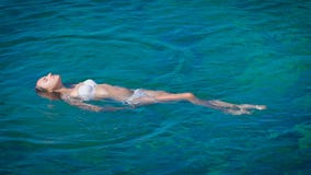 Μια νέα ευτυχής γυναίκα στο άσπρο μπικίνι που κολυμπά στην κυανή θάλασσα απόθεμα βίντεο Μια νέα ευτυχής γυναίκα στο άσπρο μπικίνι που κολυμπά στην κυανή θάλασσα απόθεμα βίντεο