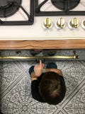 Μια πεινασμένη συνεδρίαση αγοριών δίπλα στο φούρνο στην κουζίνα στοκ φωτογραφία Μια πεινασμένη συνεδρίαση αγοριών δίπλα στο φούρνο στην κουζίνα στοκ φωτογραφία