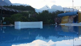 Μια πισίνα με το νερό γλιστρά μέσα ένα ξενοδοχείο στο ηλιοβασίλεμα απόθεμα βίντεο Μια πισίνα με το νερό γλιστρά μέσα ένα ξενοδοχείο στο ηλιοβασίλεμα απόθεμα βίντεο