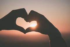 Μια χειρονομία χεριών καρδιών που σκιαγραφείται από το ηλιοβασίλεμα πέρα από Dartmoor, UK στοκ εικόνα με δικαίωμα ελεύθερης χρήσης Μια χειρονομία χεριών καρδιών που σκιαγραφείται από το ηλιοβασίλεμα πέρα από Dartmoor, UK στοκ εικόνα με δικαίωμα ελεύθερης χρήσης