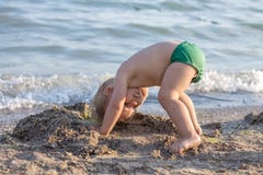 Μικρό παιδί που στέκεται στο κεφάλι του στην παραλία Στοκ Εικόνες Μικρό παιδί που στέκεται στο κεφάλι του στην παραλία Στοκ Εικόνες