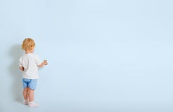 Μικρό παιδί με τη βούρτσα χρωμάτων που στέκεται πίσω κοντά στον μπλε τοίχο στοκ εικόνες Μικρό παιδί με τη βούρτσα χρωμάτων που στέκεται πίσω κοντά στον μπλε τοίχο στοκ εικόνες