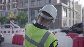 Μικρό παιδί που φορούν το επιχειρησιακό κοστούμι και τον εξοπλισμό ασφάλειας και κράνος κατασκευαστών που στέκεται σε έναν πολυάσ απόθεμα βίντεο Μικρό παιδί που φορούν το επιχειρησιακό κοστούμι και τον εξοπλισμό ασφάλειας και κράνος κατασκευαστών που στέκεται σε έναν πολυάσ απόθεμα βίντεο