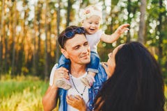 Μοντέρνη νέα οικογένεια mom, ξανθή συνεδρίαση ενός έτους βρεφών μπαμπάδων και κορών με τον πατέρα στο παιχνίδι ώμων ευτυχές και τ στοκ εικόνες Μοντέρνη νέα οικογένεια mom, ξανθή συνεδρίαση ενός έτους βρεφών μπαμπάδων και κορών με τον πατέρα στο παιχνίδι ώμων ευτυχές και τ στοκ εικόνες