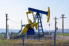 Μπλε και κίτρινος γρύλος αντλιών επάνω από μια πετρελαιοπηγή που περι στοκ φωτογραφία με δικαίωμα ελεύθερης χρήσης Μπλε και κίτρινος γρύλος αντλιών επάνω από μια πετρελαιοπηγή που περι στοκ φωτογραφία με δικαίωμα ελεύθερης χρήσης