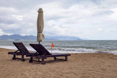 Μόνη αμμώδης παραλία με τις καρέκλες και τις ομπρέλες παραλιών κοντά στη θάλασσα στοκ φωτογραφία με δικαίωμα ελεύθερης χρήσης Μόνη αμμώδης παραλία με τις καρέκλες και τις ομπρέλες παραλιών κοντά στη θάλασσα στοκ φωτογραφία με δικαίωμα ελεύθερης χρήσης