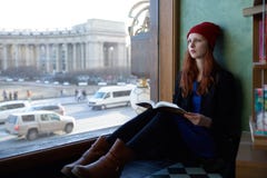 Νέα redhead συνεδρίαση σπουδαστών κοριτσιών γυναικών στο παράθυρο που διαβάζει το α στοκ φωτογραφία με δικαίωμα ελεύθερης χρήσης Νέα redhead συνεδρίαση σπουδαστών κοριτσιών γυναικών στο παράθυρο που διαβάζει το α στοκ φωτογραφία με δικαίωμα ελεύθερης χρήσης