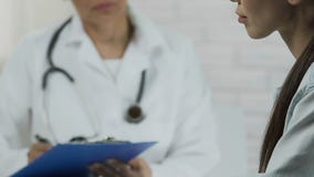 Νέα ασιατική γυναίκα που λέει τα συμπτώματα, γιατρός που ακούνε και που κρατούν τις ιατρικές αναφορές απόθεμα βίντεο Νέα ασιατική γυναίκα που λέει τα συμπτώματα, γιατρός που ακούνε και που κρατούν τις ιατρικές αναφορές απόθεμα βίντεο