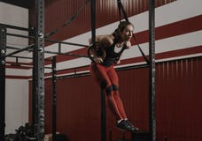 Νέα γυναίκα crossfit που κάνει το μυς-UPS στα γυμναστικά δαχτυλίδια στη γυμναστική στοκ εικόνα Νέα γυναίκα crossfit που κάνει το μυς-UPS στα γυμναστικά δαχτυλίδια στη γυμναστική στοκ εικόνα