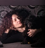 Νέα γυναίκα με poodle παιχνιδιών το σκυλί σε έναν καναπέ σε ένα σκοτεινό δωμάτιο στοκ εικόνες Νέα γυναίκα με poodle παιχνιδιών το σκυλί σε έναν καναπέ σε ένα σκοτεινό δωμάτιο στοκ εικόνες