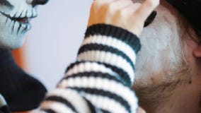 Νέα γυναίκα που εφαρμόζει το απόκοσμο makeup επάνω στο πρόσωπο ανδρών ` s σε αποκριές απόθεμα βίντεο Νέα γυναίκα που εφαρμόζει το απόκοσμο makeup επάνω στο πρόσωπο ανδρών ` s σε αποκριές απόθεμα βίντεο