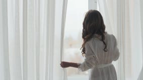 Νέα γυναίκα που στέκεται στο παράθυρο απόθεμα βίντεο Νέα γυναίκα που στέκεται στο παράθυρο απόθεμα βίντεο