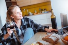 Νέα γυναίκα στο σπίτι στον κινηματογράφο προσοχής κρασιού κατανάλωσης κουζινών στοκ φωτογραφίες με δικαίωμα ελεύθερης χρήσης Νέα γυναίκα στο σπίτι στον κινηματογράφο προσοχής κρασιού κατανάλωσης κουζινών στοκ φωτογραφίες με δικαίωμα ελεύθερης χρήσης
