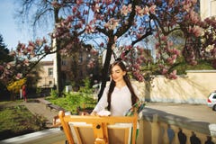 Νέα εκμετάλλευση καλλιτεχνών γυναικών brunette στα χέρια μια βούρτσα και μια παλέτα Κοντά σε την το δέντρο magnolia και ο διάφορο στοκ φωτογραφίες με δικαίωμα ελεύθερης χρήσης Νέα εκμετάλλευση καλλιτεχνών γυναικών brunette στα χέρια μια βούρτσα και μια παλέτα Κοντά σε την το δέντρο magnolia και ο διάφορο στοκ φωτογραφίες με δικαίωμα ελεύθερης χρήσης
