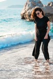 Νέα ελκυστική γυναίκα που περπατά σε μια ηλιόλουστη παραλία στην ακτή Ταξιδιώτης και blogger στοκ φωτογραφία Νέα ελκυστική γυναίκα που περπατά σε μια ηλιόλουστη παραλία στην ακτή Ταξιδιώτης και blogger στοκ φωτογραφία